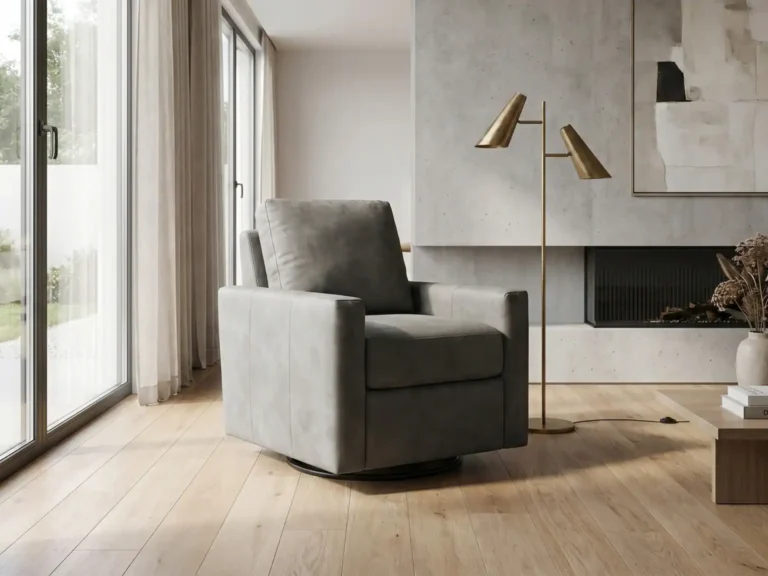 A modern gray armchair sits on light wood flooring next to a gold floor lamp in a minimalist living room with large windows and a concrete fireplace.