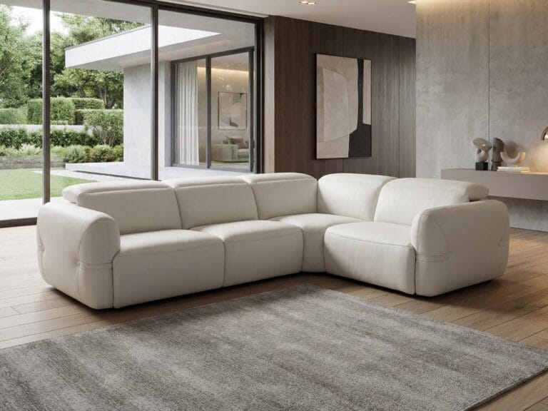 A modern living room with a large white sectional sofa, gray rug, wooden floor, and floor-to-ceiling windows showing a green outdoor area.