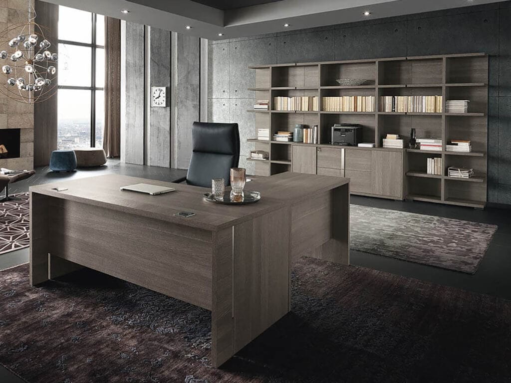 Modern office with a large wooden desk, black chair, shelves filled with books, and a window letting in natural light. The decor is minimalist with neutral tones.